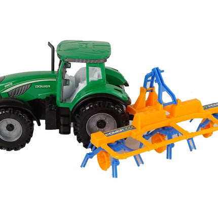 Žalias traktorius su oranžiniu ir mėlynu grėbliu, varomas trintimi
