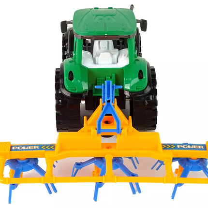 Žalias traktorius su oranžiniu ir mėlynu grėbliu, varomas trintimi