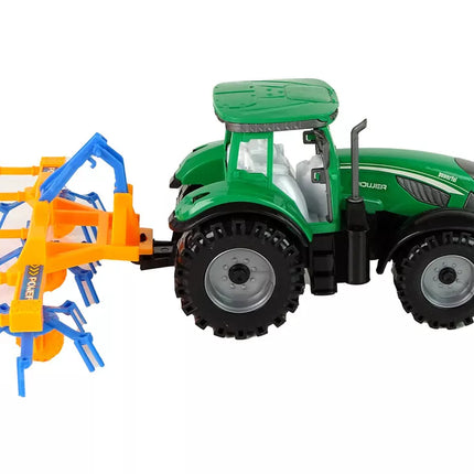 Žalias traktorius su oranžiniu ir mėlynu grėbliu, varomas trintimi
