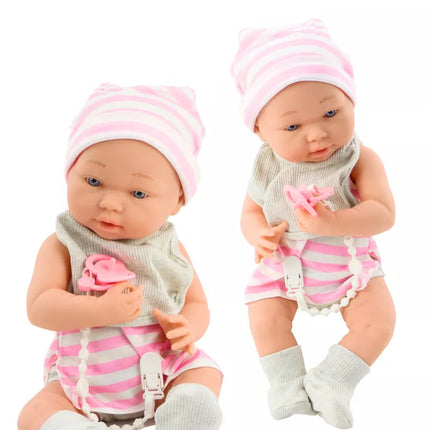 Lėlytė su baltais ir rožiniais drabužėliais, kepuryte, čiulptuku, seilinuku, antklode