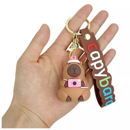 Raktų pakabukas su kapibaros figūrėle, kameros ir kepurės pakabuku bei karabino žiedu